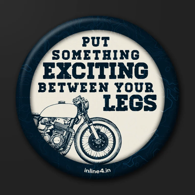 Navy badge with a topographic map background, cream text reading "Put Something Exciting Between Your Legs," and a line-art motorcycle illustration