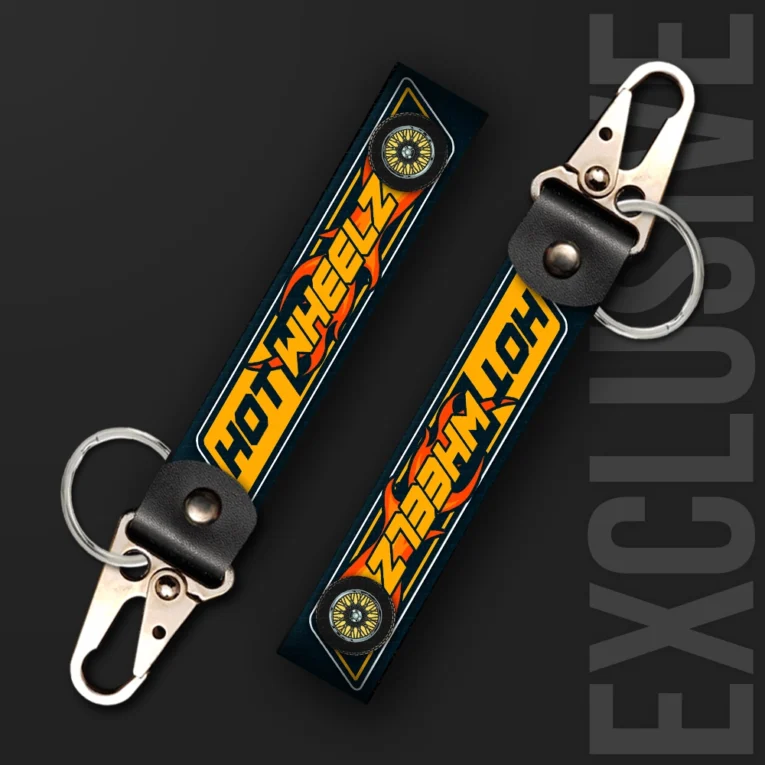 Inline-4 Hot Wheelz keychain strap with orange flame lettering, alloy-wheel icons, and a navy diamond-plate background, swivel hook clip + keyring