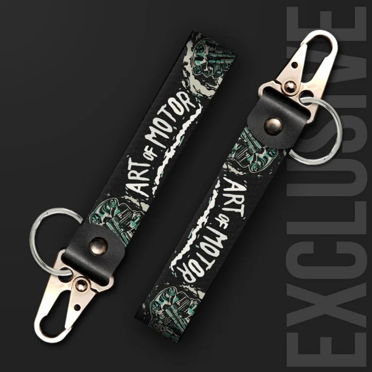 Inline-4 Art of Motor keychain strap with white 'ART OF MOTOR' text over teal engine-piston illustrations on black, swivel hook clip + keyring