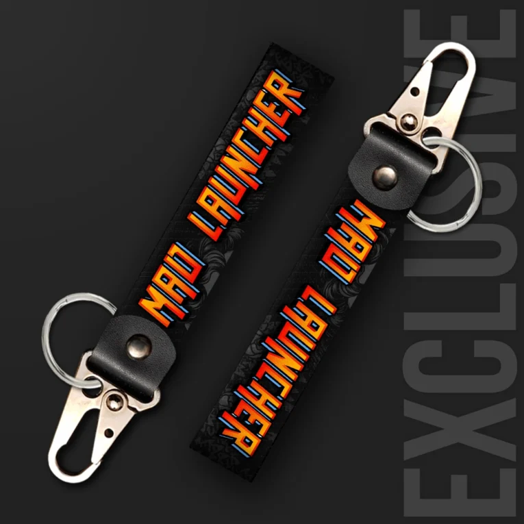 Inline-4 Mad Launcher keychain strap with retro arcade-style orange and red 'MAD LAUNCHER' text on a dark textured background, swivel hook clip + keyring