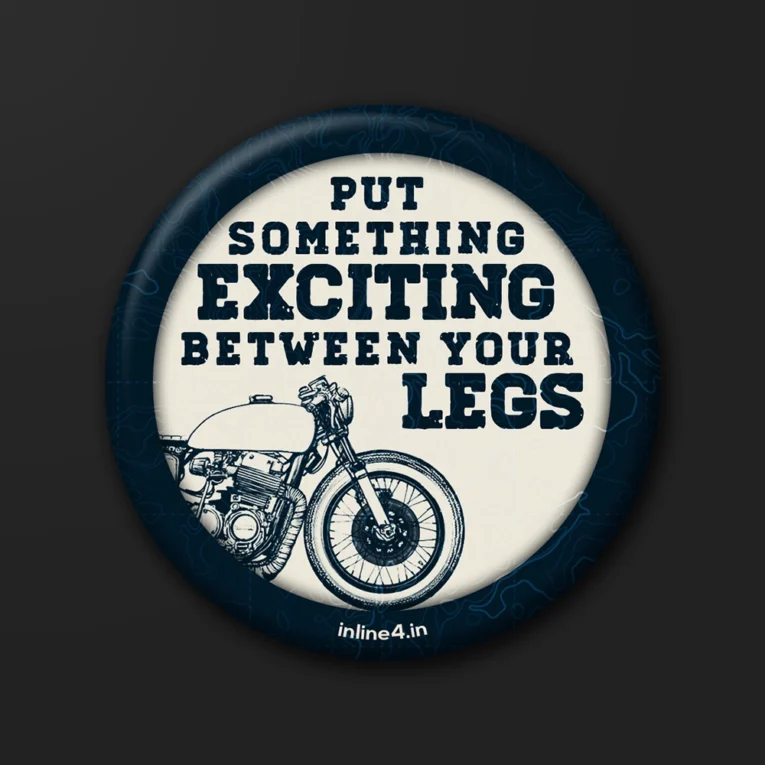 Navy badge with a topographic map background, cream text reading "Put Something Exciting Between Your Legs," and a line-art motorcycle illustration