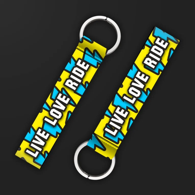Inline-4 Live Love Ride keychain strap with bold white 'LIVE LOVE RIDE' text over a yellow and blue lightning-bolt pattern, double keyring
