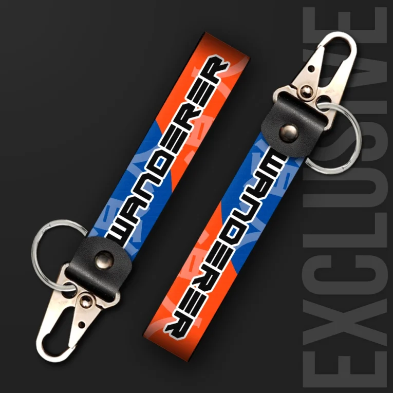 Inline-4 Wanderer keychain strap with bold black 'WANDERER' text over an orange and blue geometric background, swivel hook clip + keyring
