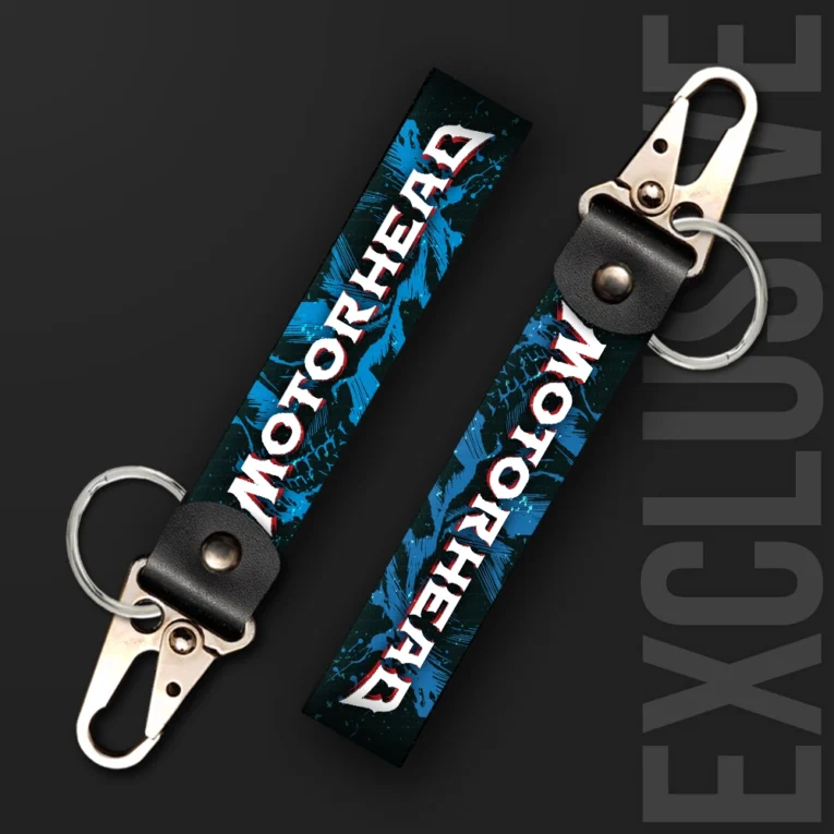 Inline-4 Motorhead keychain strap with a bold white and red 'MOTORHEAD' wordmark over a blue splatter-paint background, swivel hook clip + keyring