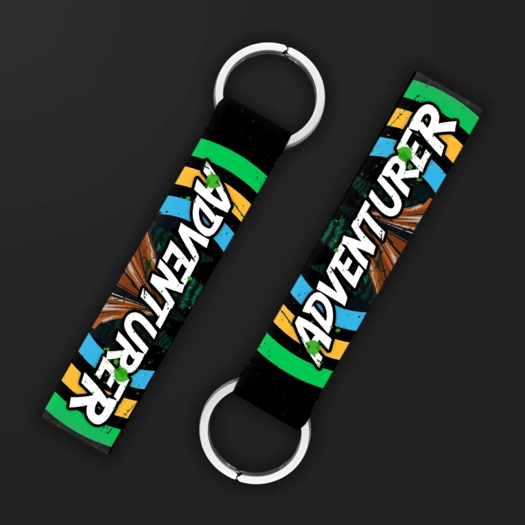 Inline-4 Adventurer keychain strap with white graffiti-style 'ADVENTURER' text over a green, orange, and blue striped background, double keyring
