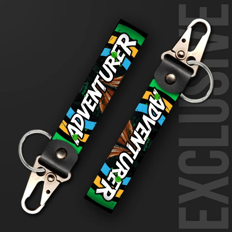 Inline-4 Adventurer keychain strap with white graffiti-style 'ADVENTURER' text over a green, orange, and blue striped background, swivel hook clip + keyring