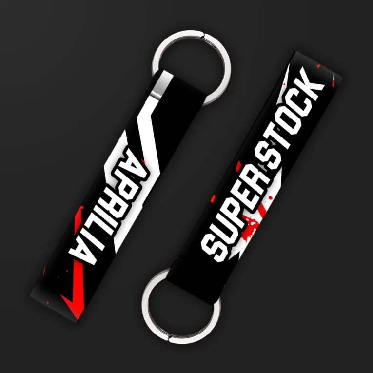 Inline-4 Superstock keychain strap with bold white 'SUPER STOCK' text and a red checkmark stripe on a black splatter background, double keyring