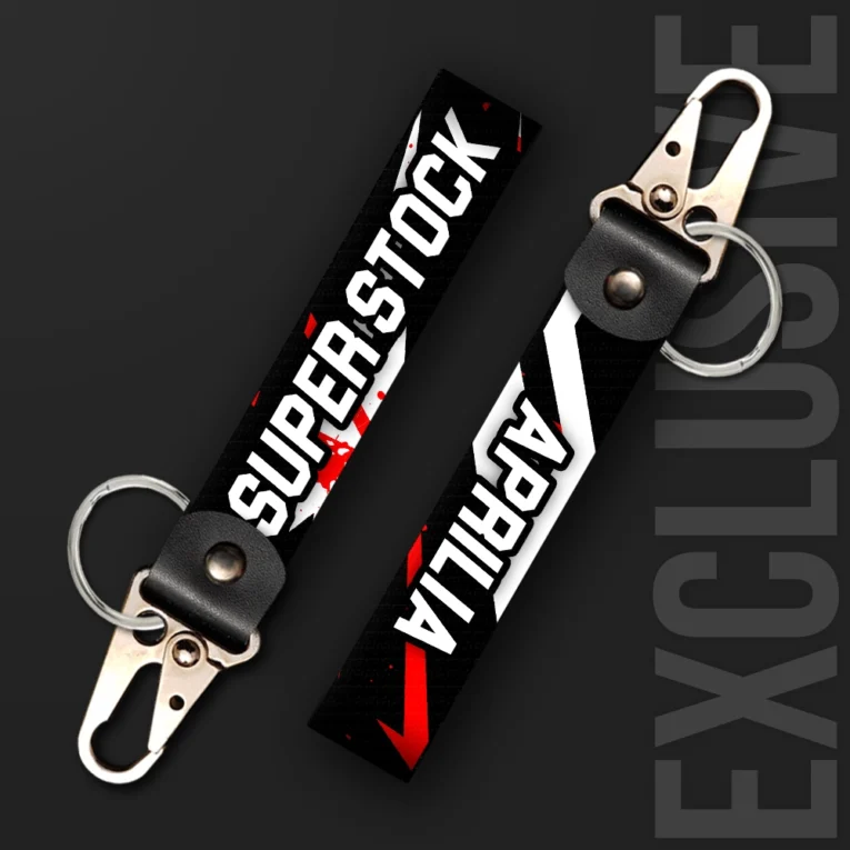 Inline-4 Superstock keychain strap with bold white 'SUPER STOCK' text and a red checkmark stripe on a black splatter background, swivel hook clip + keyring
