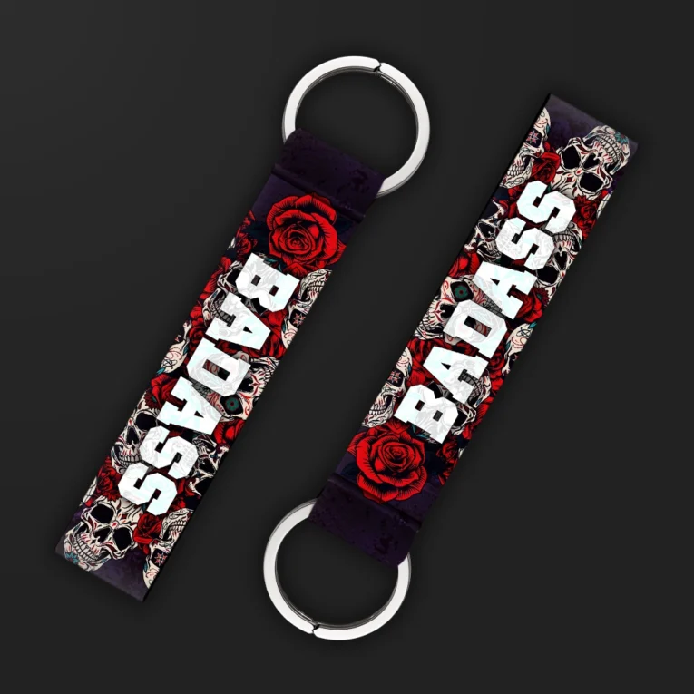 Inline-4 Badass keychain strap with bold white 'BADASS' text over a red rose and sugar-skull illustration on black, double keyring