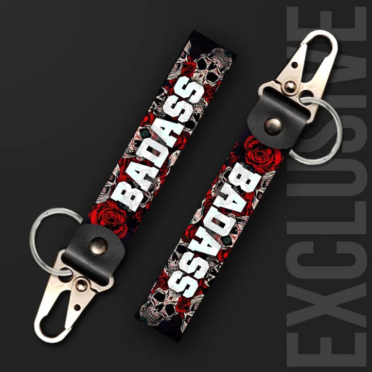 Inline-4 Badass keychain strap with bold white 'BADASS' text over a red rose and sugar-skull illustration on black, swivel hook clip + keyring