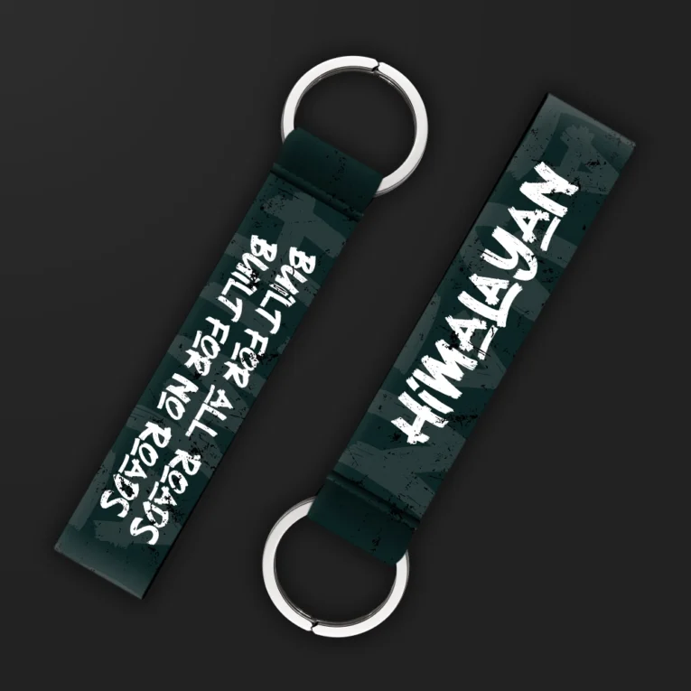 Inline-4 Himalayan keychain strap with white 'HIMALAYAN' text and 'BUILT FOR ALL ROADS, BUILT FOR NO ROADS' tagline on a dark green background, double keyring