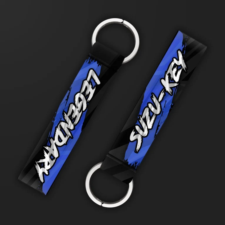 Inline-4 Suzukey keychain strap with bold white brush-lettered 'SUZU-KEY' and 'LEGENDARY' text on a blue background, double keyring