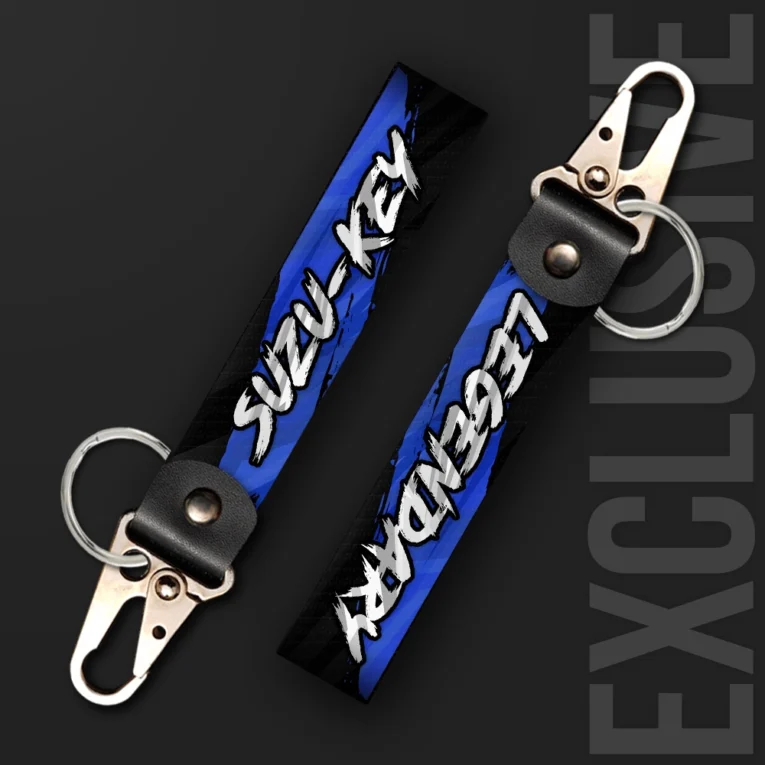 Inline-4 Suzukey keychain strap with bold white brush-lettered 'SUZU-KEY' and 'LEGENDARY' text on a blue background, swivel hook clip + keyring