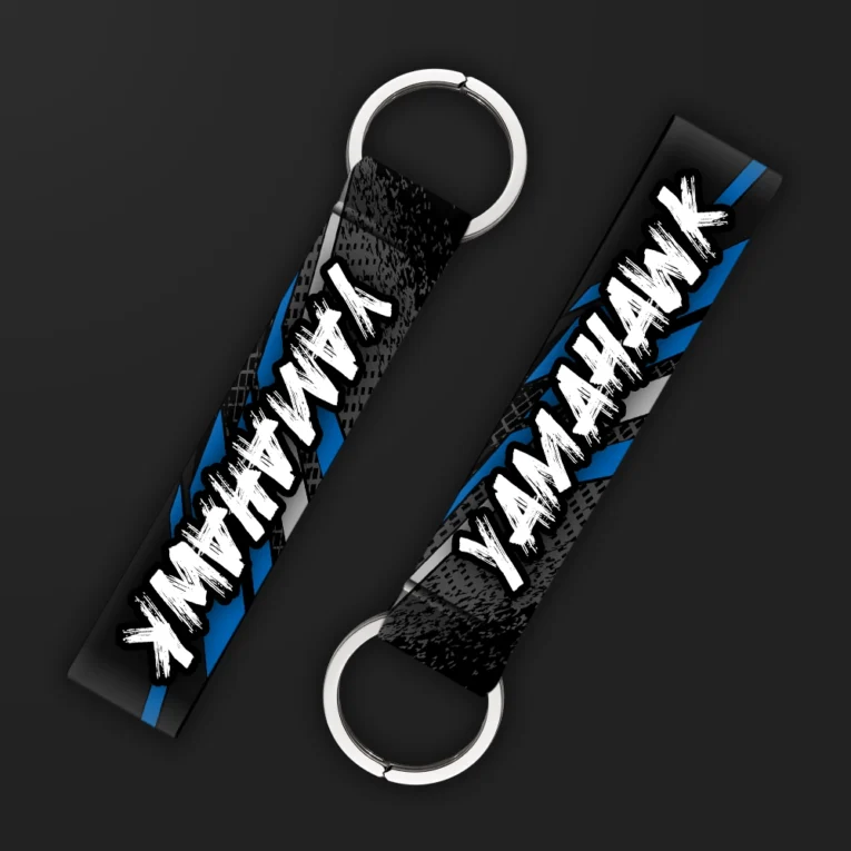 Inline-4 Yamahawk keychain strap with bold white brush-lettered 'YAMAHAWK' text on a black and blue tire-tread background, double keyring