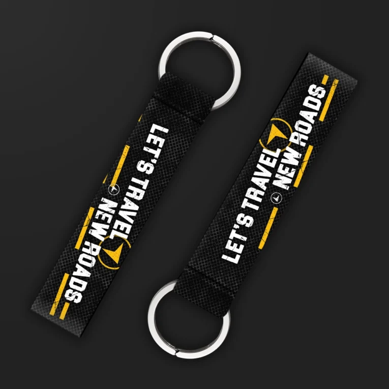 Inline-4 Lets Travel New Roads keychain strap with white 'LET'S TRAVEL NEW ROADS' text and a compass icon on black, double keyring