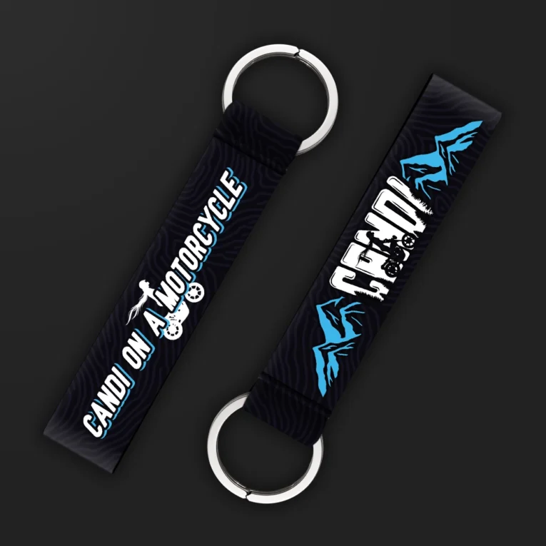 Inline-4 Candi on a Motorcycle keychain strap with a blue mountain illustration, 'CANDI' text, and a rider silhouette icon on black, double keyring