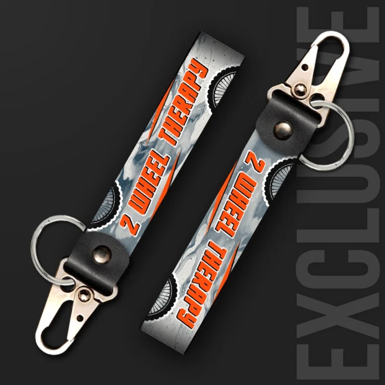Inline-4 Two Wheel Therapy keychain strap with orange 'TWO WHEEL THERAPY' text over a grey marbled background with wheel icons, swivel hook clip + keyring