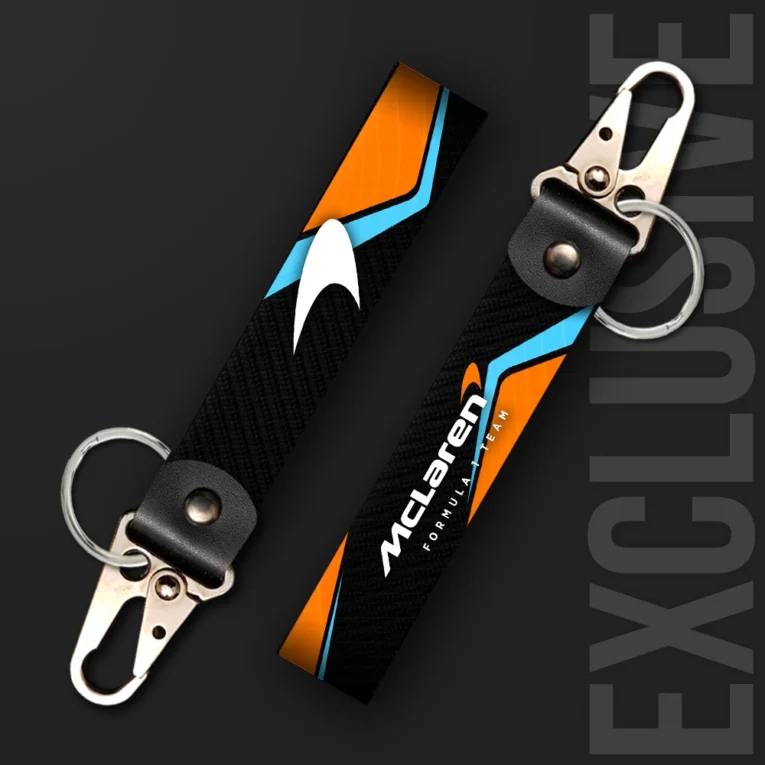 Inline-4 racing tribute keychain strap in McLaren-inspired orange and blue with an arrow-mark graphic, swivel hook clip + keyring