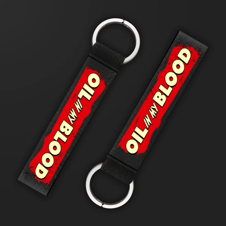 Inline-4 Oil in my Blood keychain strap with a red paint-splash background and cream 'OIL IN MY BLOOD' lettering, double keyring
